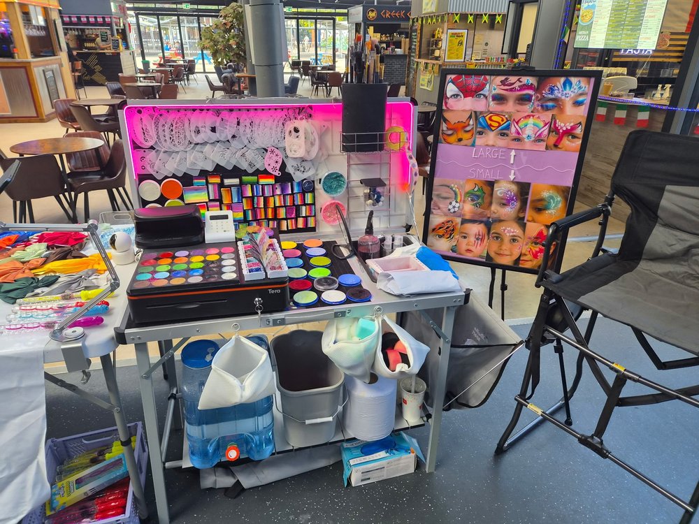 CL Paints event setup with colourful palettes, brushes and a face painting design board